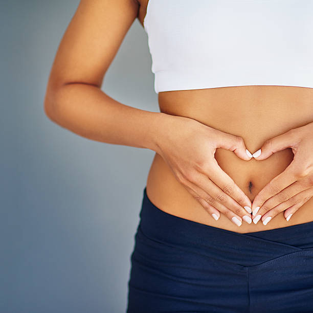 Woman holding heart-shape over abdomen representing gut health and microplastic detox in Chicago at Bliss MD