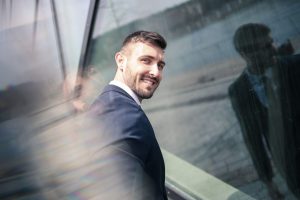 Low testosterone and ED: smiling businessman beside a glass wall