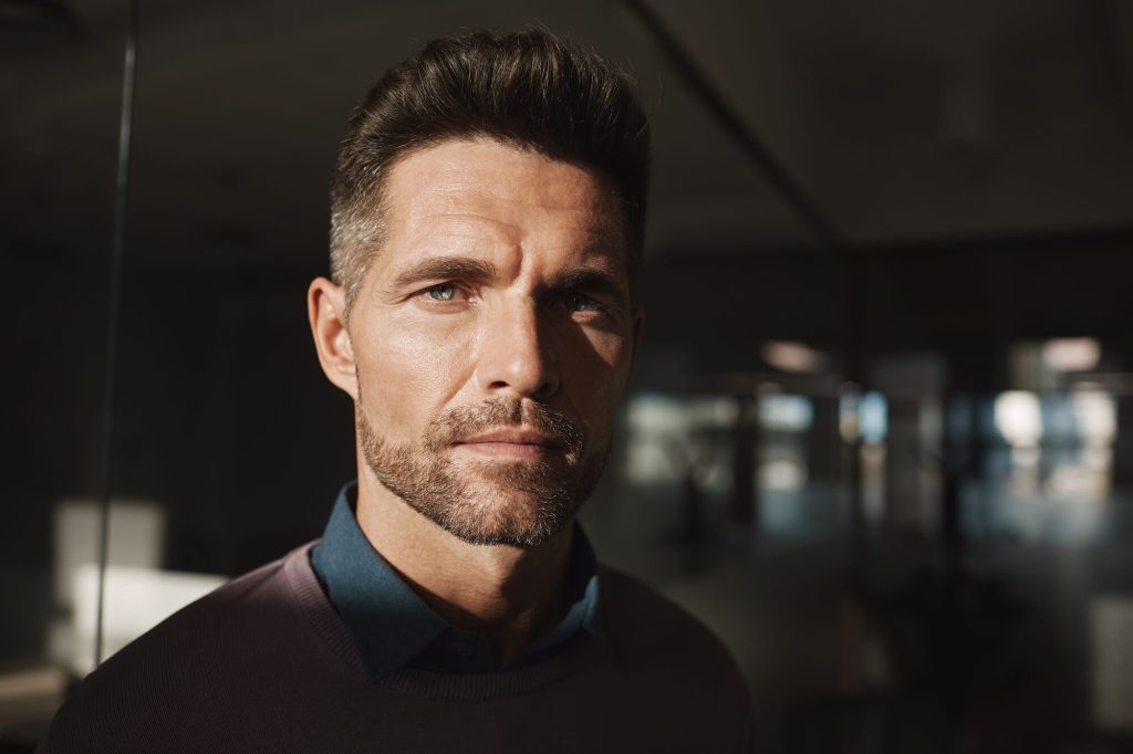 Low testosterone symptoms: man in a dark sweater at an office