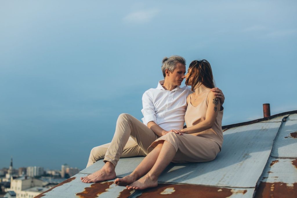 Couple in their 50s sitting close together on a rooftop above the city
