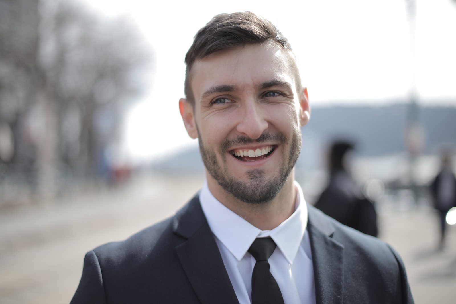 Testosterone pellets for men in Chicago: smiling man in a dark suit and tie outdoors on a sunny promenade