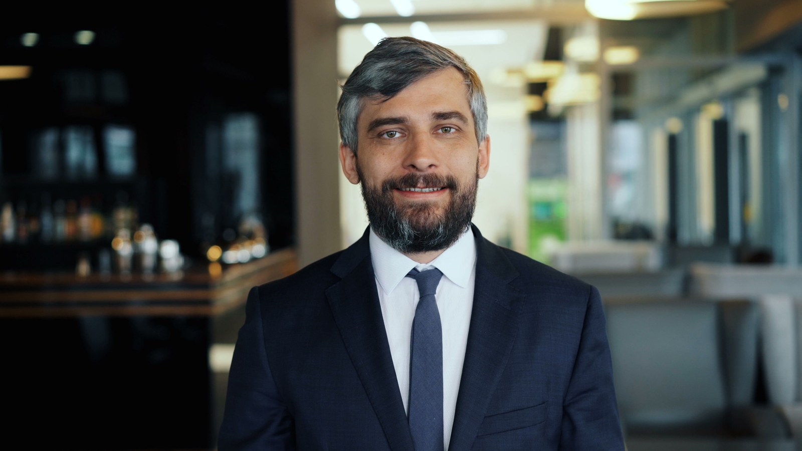 Testosterone replacement therapy Chicago: smiling bearded man in a navy suit and tie in a softly lit lounge